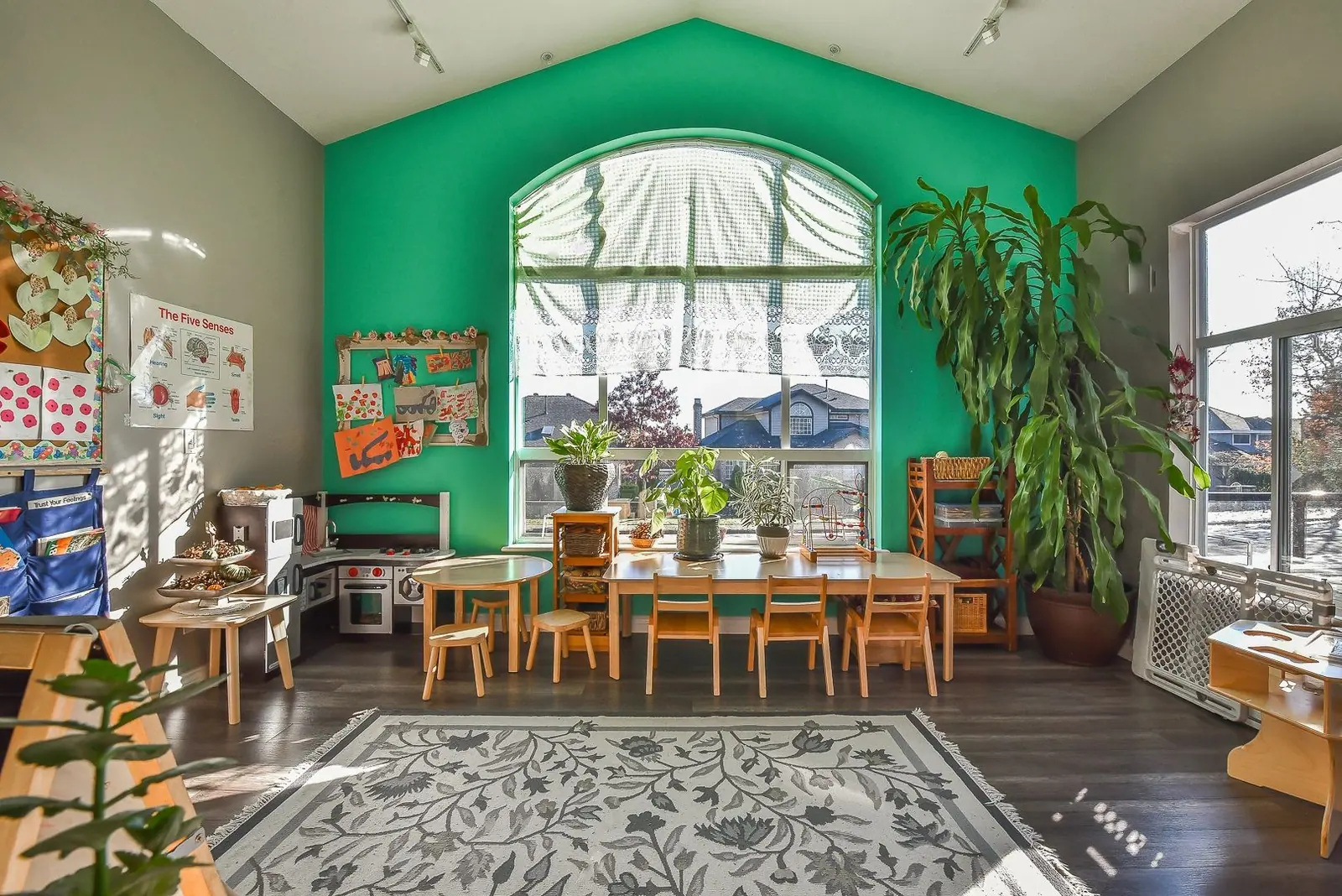 The centre's brightest learning room, with a tall arched window, long wooden tables and plants